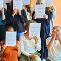 Gruppe von Yogastudierende halten ihre Zertifikate vor das Gesicht