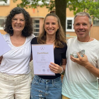 Pascal Portmann und Nathalie Üstünay von Yoga Veda Ausbildungen mit einer Yogaschülerin die stolz Ihr Yogalehreinnen Zertifikat in den Händen hält