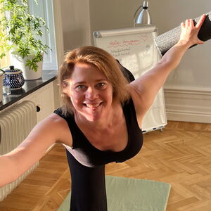 Yogalehrerin mit verschiedenen Faszienrollen in der Standwaage